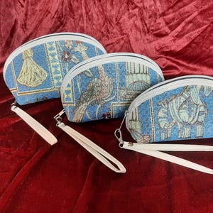 Könnte beinhalten: Drei blaue und weiße Kosmetiktaschen aus Tapisserie mit Reißverschluss und weißen Bändern. Die Taschen haben verschiedene Muster, darunter einen Vogel, ein Blumenmuster und ein geometrisches Muster.