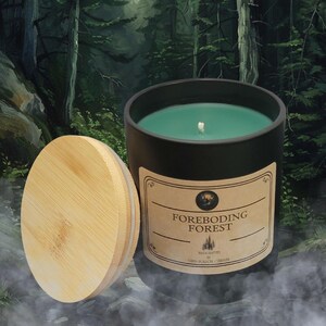 May include: A black candle jar with a green wax candle inside. The jar has a label that reads "Foreboding Forest" and is topped with a wooden lid.
