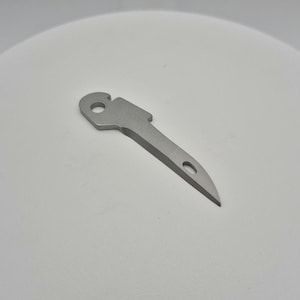 May include: A silver metal tool with a pointed tip and a hole in the handle.