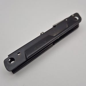 May include: A matte black multi-tool with a folding design, featuring a circular hole at one end and the engraved text 45N 122W on the side. The tool has a slim, elongated profile with a metallic silver pivot screw and a visible internal blade edge.