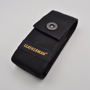 May include: Black nylon Leatherman sheath with a snap closure. The Leatherman logo is printed in gold on the front. The sheath is designed to hold a multi-tool.