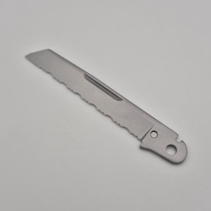 May include: A stainless steel serrated knife blade with a rounded tip and a hole at the base. The blade has a single groove and a series of teeth along the cutting edge. The knife is designed for cutting.