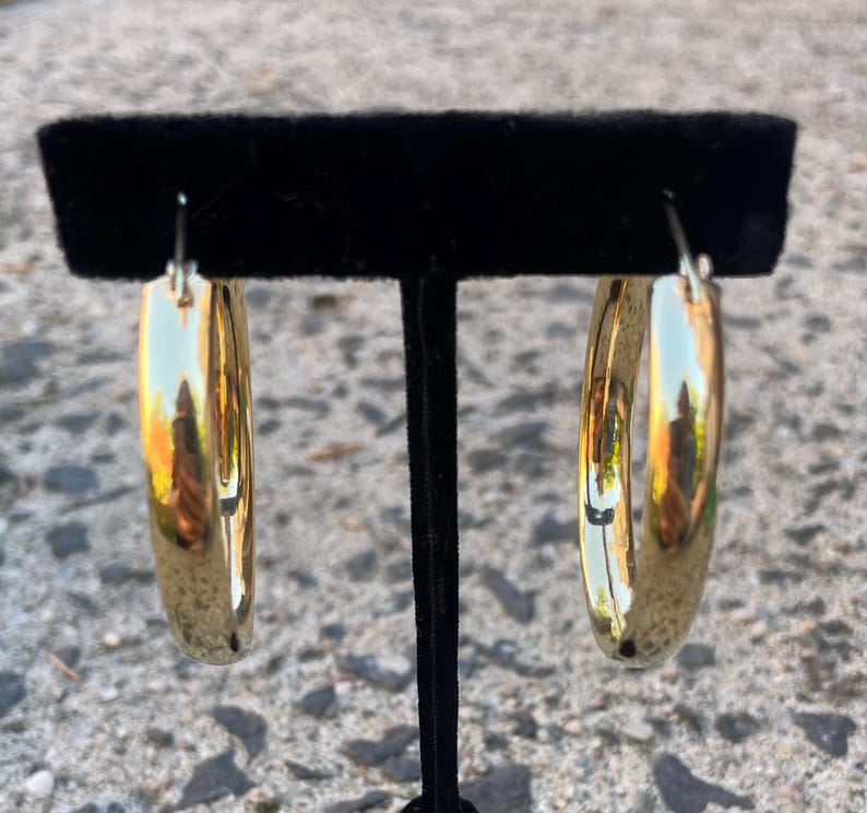 May include: A pair of gold hoop earrings. The earrings are large and have a smooth, polished finish.