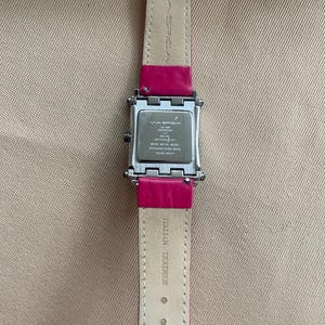 Puede incluir: Un reloj plateado con una esfera cuadrada y una correa de cuero rosa. La esfera del reloj tiene el texto "MA SPIGA" y "ESPRESSO" en ella. La correa tiene el texto "ITALIAN LEATHER" en ella.