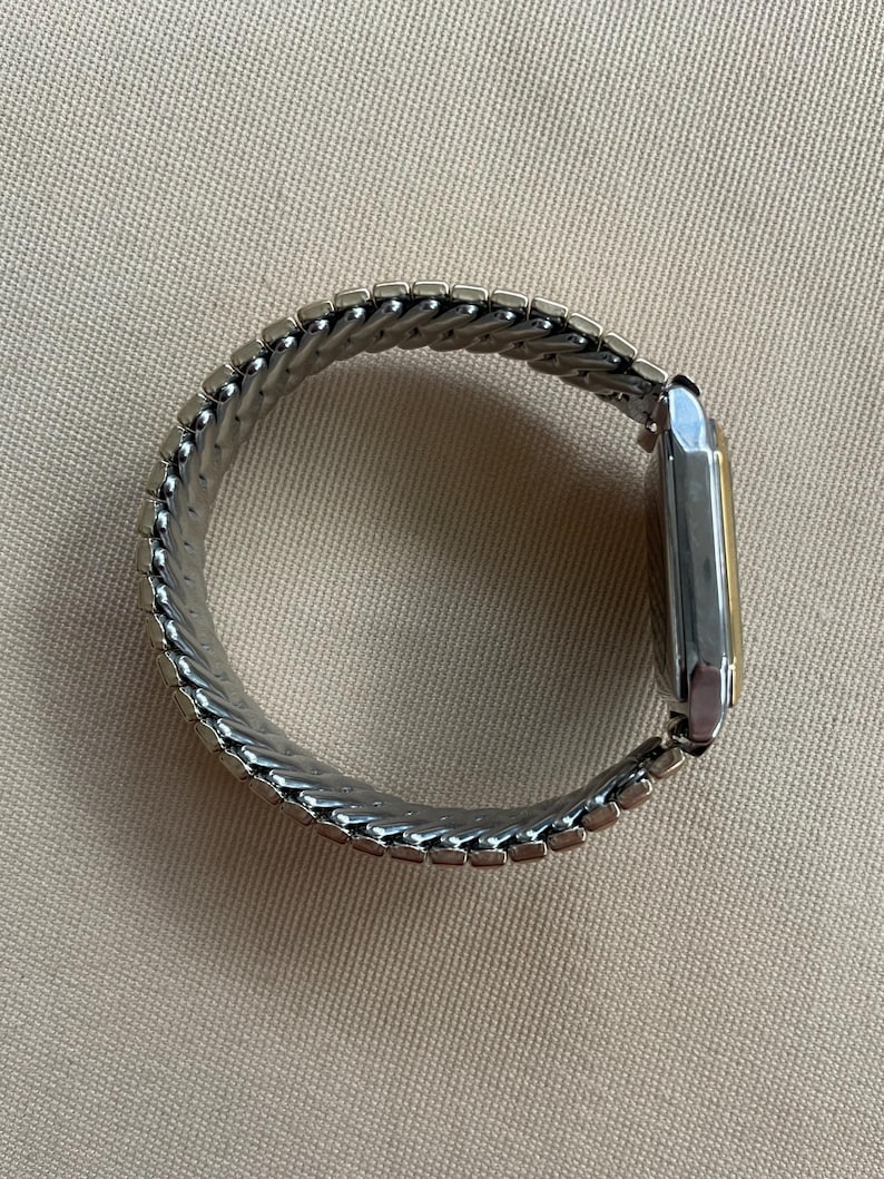 Peut inclure: Une montre argent&eacute;e avec un cadran carr&eacute; et un bracelet en m&eacute;tal argent&eacute;. Le bracelet est compos&eacute; de petites pi&egrave;ces reli&eacute;es qui cr&eacute;ent un ajustement flexible et confortable.