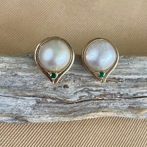 May include: A pair of gold earrings with a white pearl and a green gemstone accent.