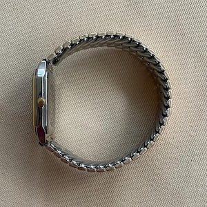 Peut inclure: Une montre argent&eacute;e et dor&eacute;e avec un cadran carr&eacute; et un bracelet en m&eacute;tal.