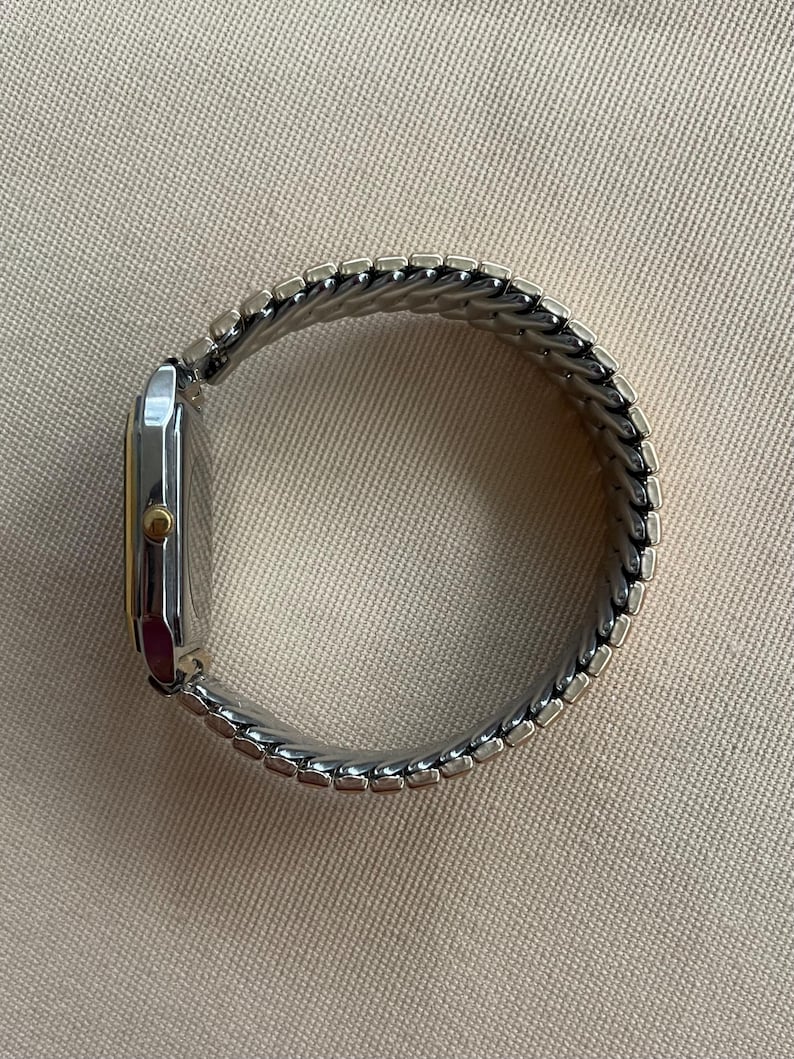 Peut inclure: Une montre argent&eacute;e et dor&eacute;e avec un cadran carr&eacute; et un bracelet en m&eacute;tal.