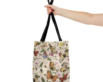 May include: A beige tote bag with black straps featuring a pattern of colorful butterflies and flowers.