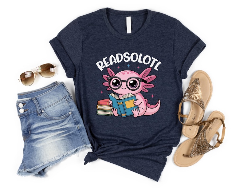 Puede incluir: Camiseta azul marino con un ajolote de dibujos animados con gafas y leyendo un libro. El texto "READSOLOTL" est&aacute; encima del ajolote. Tambi&eacute;n se ven unos pantalones cortos vaqueros y sandalias.