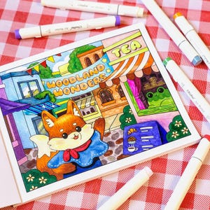 Op de afbeelding: Een kleurplaat met een cartoonvos in een blauwe outfit, met de tekst "Woodland Wonders". De pagina is gekleurd met verschillende stiften, waaronder paars, groen en oranje. De sc&egrave;ne omvat een theehuis en een kikker.