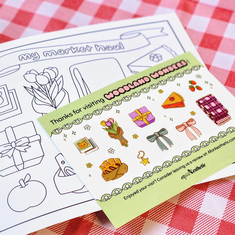 Op de afbeelding: Een groene kaart met de tekst "Thanks for visiting Woodland Wonders" en verschillende illustraties van cadeaus, bloemen en eten. Op de achtergrond een zwart-wit kleurplaat met de tekst "my market haul".