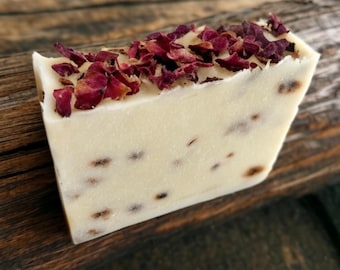 May include: A white bar of soap with dried rose petals on top. The soap has a speckled appearance.