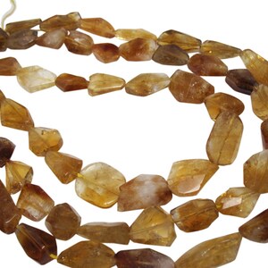 May include: A strand of golden brown gemstone beads, each bead is faceted and has a unique shape. The beads are strung on a clear thread and are ready to be used for jewelry making.