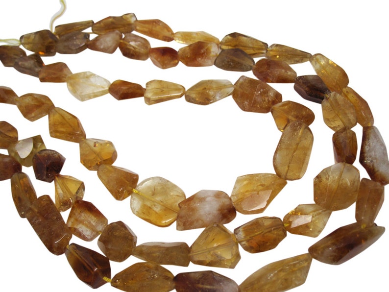 May include: A strand of golden brown gemstone beads, each bead is faceted and has a unique shape. The beads are strung on a clear thread and are ready to be used for jewelry making.