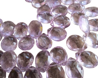 May include: A strand of faceted amethyst beads in a pale lavender color. The beads are oval shaped and have a smooth, polished finish.
