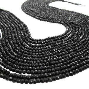 May include: A strand of black faceted gemstone beads. The beads are round and have a smooth, polished finish.
