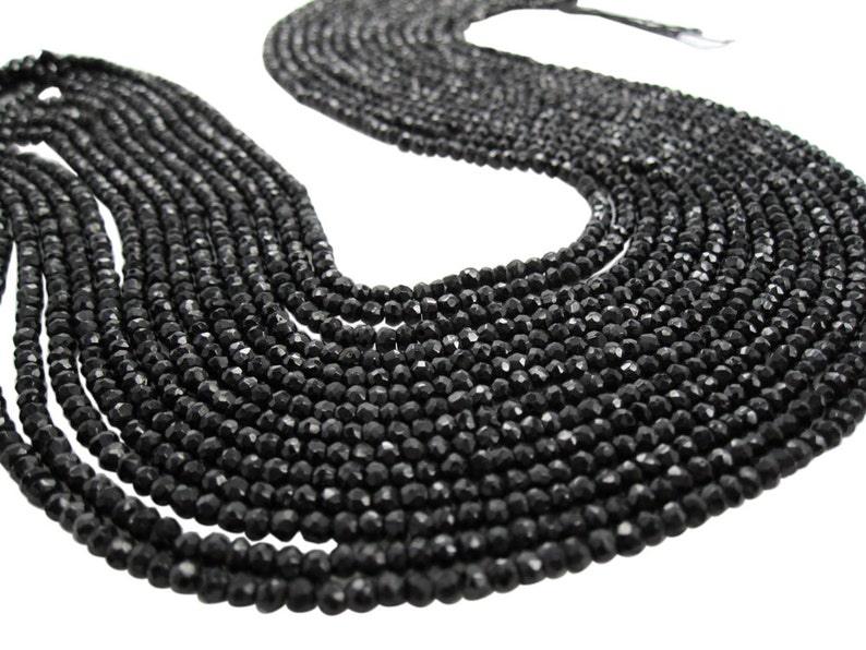 May include: A strand of black faceted gemstone beads. The beads are round and have a smooth, polished finish.