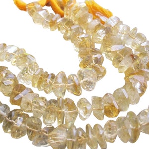 May include: Strands of faceted, irregular-shaped citrine gemstone beads. The beads are a translucent yellow-orange color, strung together with yellow thread. The background is white.