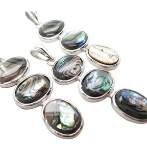 Pode incluir: V&aacute;rios pingentes de prata com incrusta&ccedil;&otilde;es ovais de concha de abalone. Cada pingente apresenta tr&ecirc;s pe&ccedil;as de concha em sequ&ecirc;ncia, com cores iridescentes de verde, azul e branco. Os pingentes s&atilde;o exibidos em fundo branco.