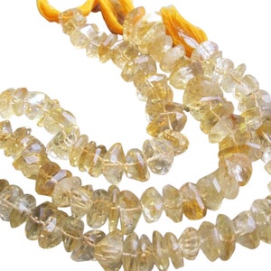 May include: Strands of faceted, light yellow citrine gemstone beads. The beads are irregular in shape and strung together with a yellow cord, creating a natural and earthy aesthetic. Ideal for jewelry making.