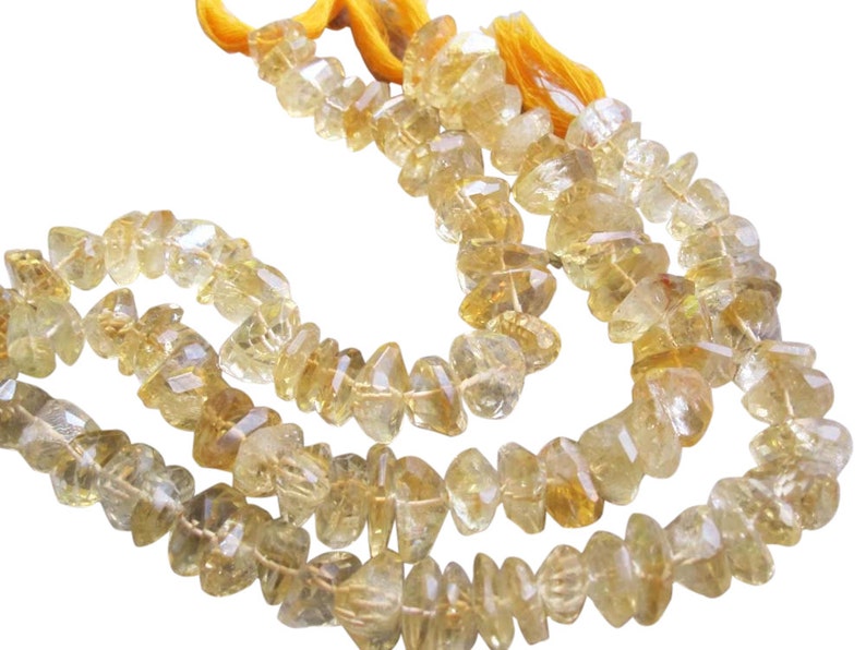 May include: Strands of faceted, light yellow citrine gemstone beads. The beads are irregular in shape and strung together with a yellow cord, creating a natural and earthy aesthetic. Ideal for jewelry making.