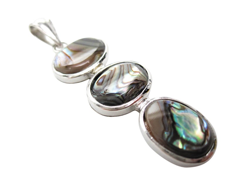 Pode incluir: Um pingente de prata com tr&ecirc;s conchas de abalone ovais. As conchas exibem cores iridescentes de verde, azul e marrom. O pingente tem um design simples e elegante.