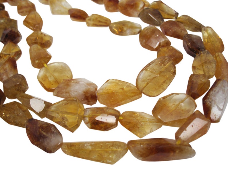May include: A strand of faceted, golden brown citrine beads. The beads are irregular in shape and have a translucent appearance.