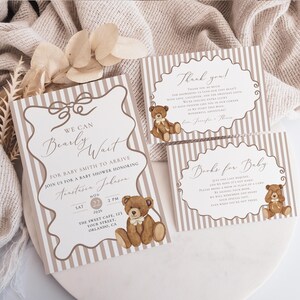 Op de afbeelding: Babydouche-uitnodigingsset met een teddybeerthema. De set bevat een uitnodiging, een bedankkaart en een boekverzoekkaart. De kaarten hebben een gestreepte achtergrond met strik- en teddybeerillustraties. De uitnodiging luidt "We Can Bearly Wait".
