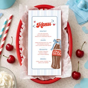 May include: A menu card with a blue and white striped design, featuring the word "Menu" in red script. The menu includes starters, main courses, desserts, and drinks. A red basket holds the menu, cherries, and straws.