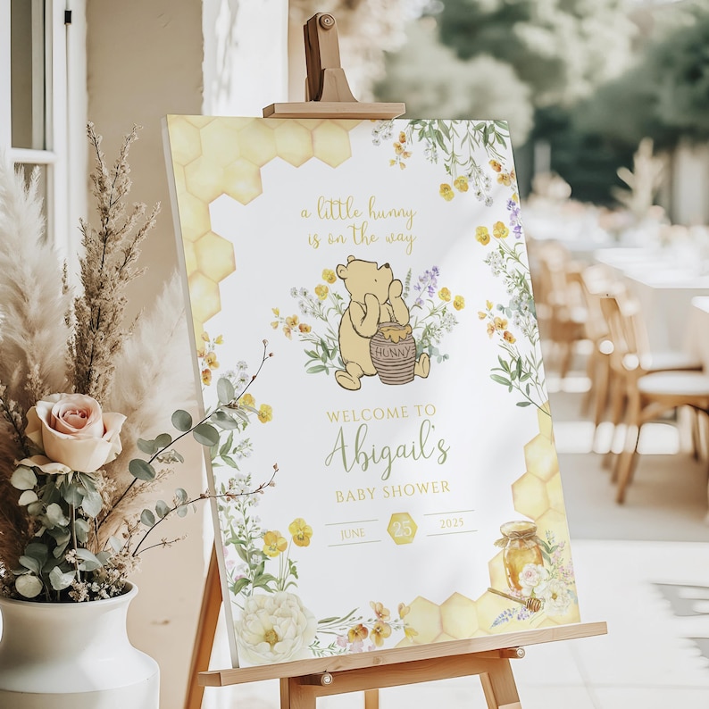 Puede incluir: Un letrero de bienvenida para baby shower con Winnie the Pooh. El letrero incluye el texto "a little hunny is on the way" y "Welcome to Abigail's Baby Shower". Decorado con dise&ntilde;os florales y de panal.