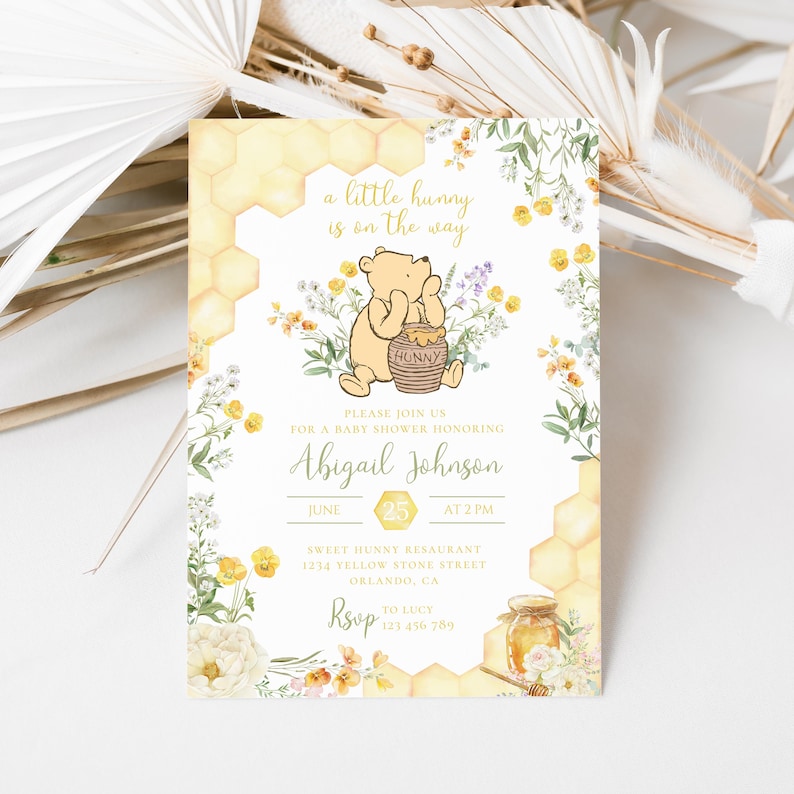 May include: Baby shower invitation featuring Winnie the Pooh. The design includes a cartoon illustration of Pooh Bear with a honey pot, floral accents, and honeycomb patterns. The invitation text reads "a little hunny is on the way" and includes event details.