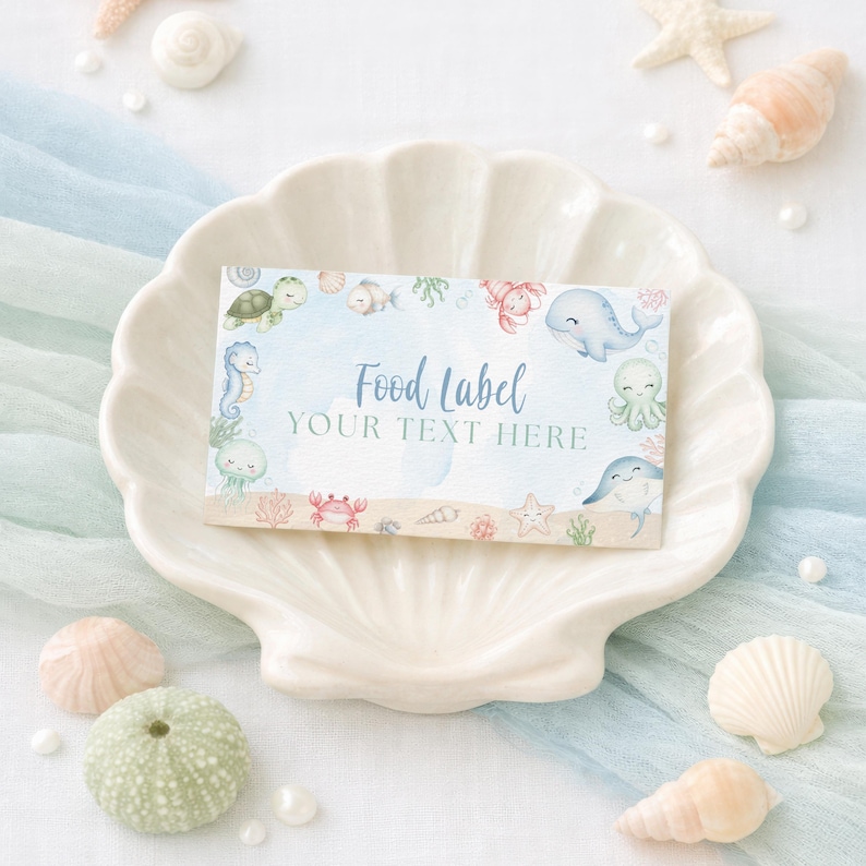 K&ouml;nnte beinhalten: Ein rechteckiges Lebensmitteletikett mit einem Aquarelldesign von Meeresbewohnern, darunter eine Schildkr&ouml;te, ein Seepferdchen und ein Wal. Das Etikett tr&auml;gt die Aufschrift "Food Label" und "Your Text Here" in eleganter Schrift. Das Etikett liegt auf einem wei&szlig;en, muschelf&ouml;rmigen Teller.
