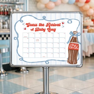 May include: A white sign with a calendar grid and the text "Guess the Arrival of Baby Long." A brown soda bottle illustration with a blue bow is on the right. The sign is on a silver stand.