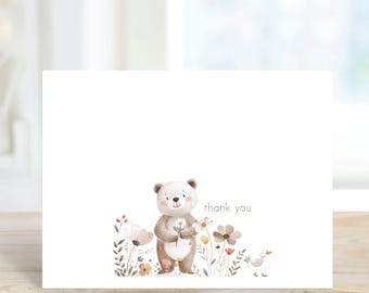 May include: A white thank you card with a brown bear holding a flower. The bear is surrounded by flowers and greenery. The text "thank you" is printed in brown on the card.