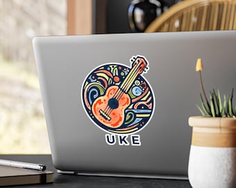 Pode incluir: Um autocolante colorido com uma ilustração de ukulele. O ukulele é laranja com detalhes pretos, rodeado por um design azul e amarelo. A palavra "UKE" está impressa em branco sobre um fundo azul.