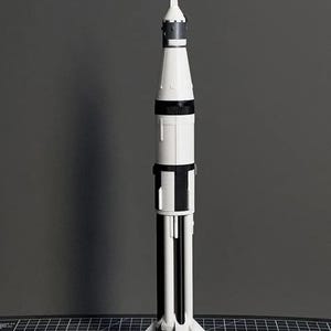May include: A white and black model of the Saturn 1B rocket on a black base with the text "SATURN 1B".
