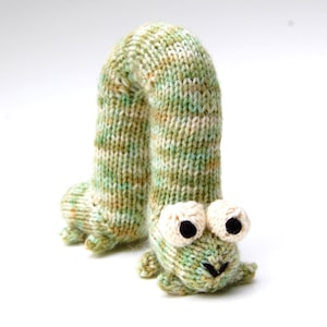 May include: A green and white striped knitted caterpillar toy with large white eyes and a black nose.