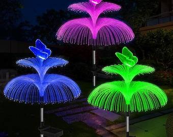 May include: Three solar-powered garden lights with butterfly toppers. The lights are in blue, green, and purple, with fiber optic strands radiating from the base. Each light has a silver pole and a black solar panel at the base.