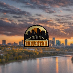 May include: Embroidered patch depicting the Edmonton skyline in black and gold. The patch is semi-circular, with 'EDMONTON' in gold lettering. The background shows a sunset over a river and city.