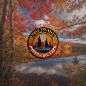 Può includere: Una toppa rotonda ricamata con le parole "Algonquin Provincial Park" in un cerchio giallo con un bordo rosso e arancione. La toppa presenta un'immagine stilizzata di un lago con tre alberi e una luna.