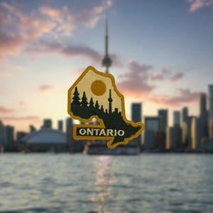 May include: A patch in the shape of Ontario, Canada, with a gold border. The patch features a silhouette of trees, a sun, and the Toronto skyline. The word "ONTARIO" is printed in white.