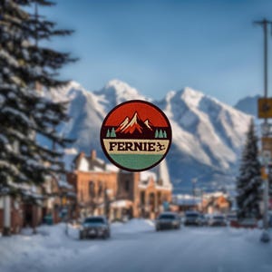 May include: A round, colourful patch with a mountain range design and the word "FERNIE" in white text. The patch has a red, orange, and yellow mountain range with a green background and a blue border.