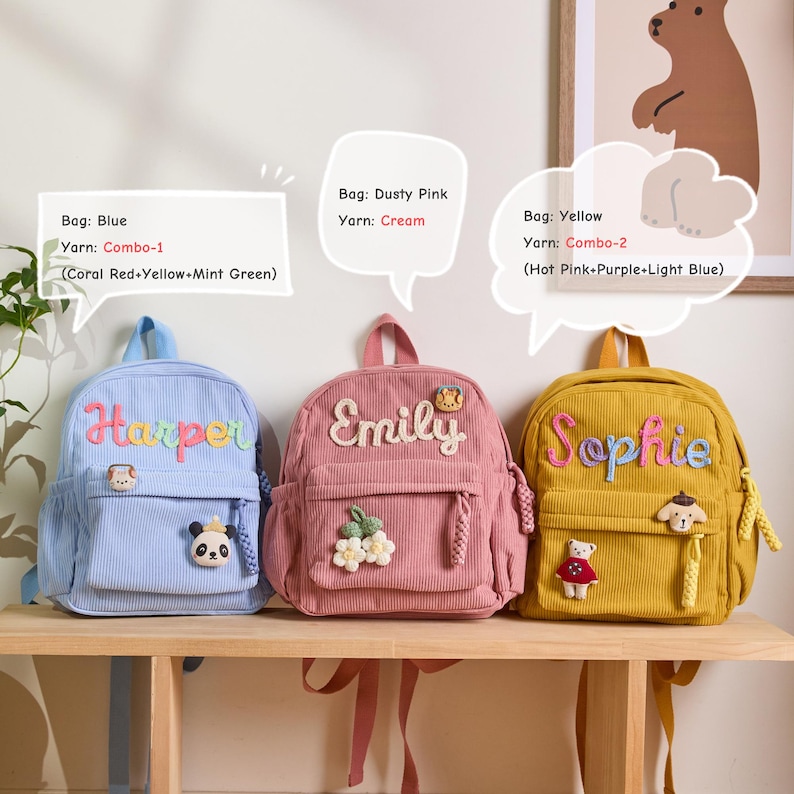 K&ouml;nnte beinhalten: Drei Cord-Rucks&auml;cke in Blau, Staubrosa und Gelb. Jeder Rucksack hat einen gestickten Namen: Harper, Emily und Sophie. Der blaue Rucksack hat einen Panda-Aufn&auml;her, der rosa einen Blumen-Aufn&auml;her und der gelbe einen Hunde-Aufn&auml;her.