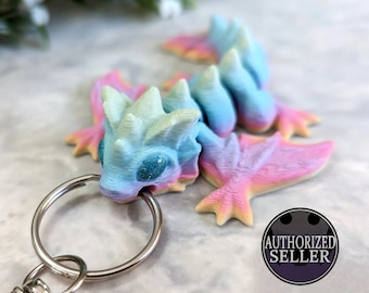 Ready to ship, rainbow pastel tiny wyvern style dragon keychain made using an articulated 3d printed Cinderwing3d design