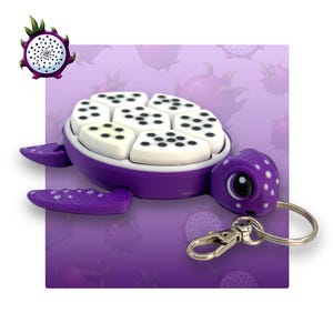 May include: Purple turtle keyring with a white shell and black dots. The shell is made of multiple pieces that can be moved around. The turtle has a cute face with a single eye and a small mouth. The keyring is attached to a silver metal ring.