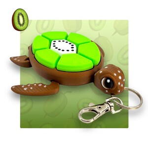 May include: A brown turtle-shaped keyring with a green kiwi fruit design on its shell. The turtle has a detailed head and flippers, and a silver clasp and keyring. A slice of kiwi fruit is also shown.