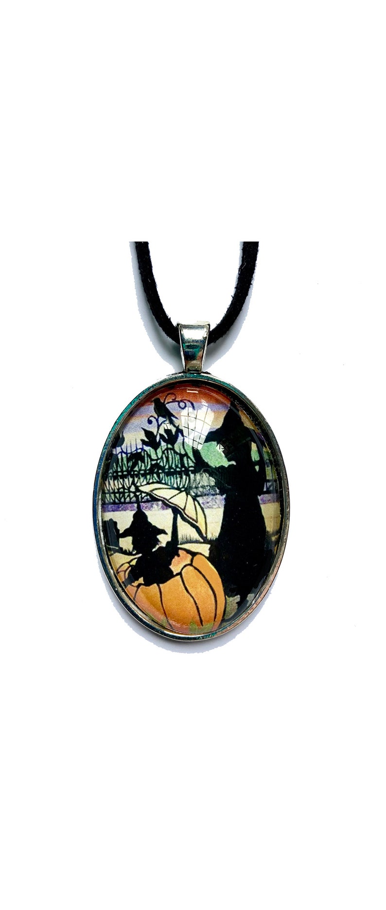May include: A black glass pendant necklace with a black cat silhouette and a pumpkin on a colorful background. The necklace has a black cord.