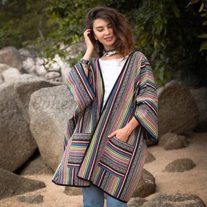 May include: A colorful, open-front kimono-style jacket with vertical stripes in various colors, including red, blue, green, and gray. The jacket has pockets and a black trim. The garment is worn over a white top and blue jeans.