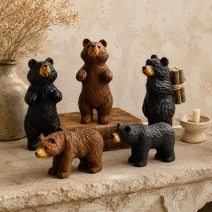 May include: A collection of five bear figurines carved from wood, featuring three standing bears and two walking bears. The bears are finished in black and brown tones with textured surfaces, and one black bear carries a bundle of small wooden sticks.